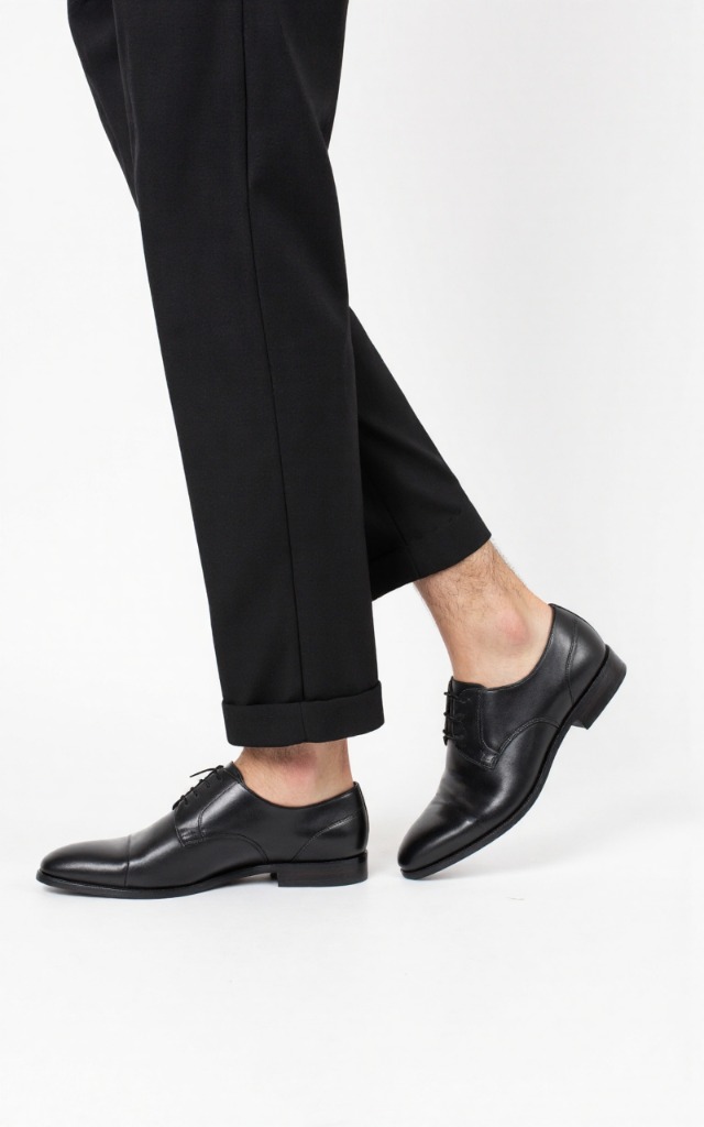 A male model wearing Dress shoes, against a white background, with a close   up of the feet